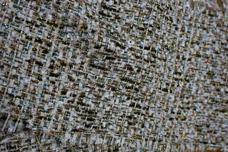 Detailed macro image of premium Chanel-style bouclé fabric with intricate woven texture and glittery threads, representing Fursone’s heritage cable knits and bespoke fabric development. This photo highlights our expertise in luxury tweed and knit sourcing with 100m ready stock and custom MOQ solutions.