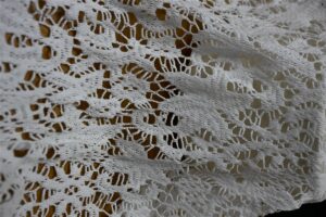 Detailed close-up of intricately knitted white bouclé fabric showcasing premium texture and artisan craftsmanship, representing Fursone's Chanel-Style Bouclé Fabric with 100M meters ready stock for global high-end fashion brands sourced from Wenzhou Textile Expertise.