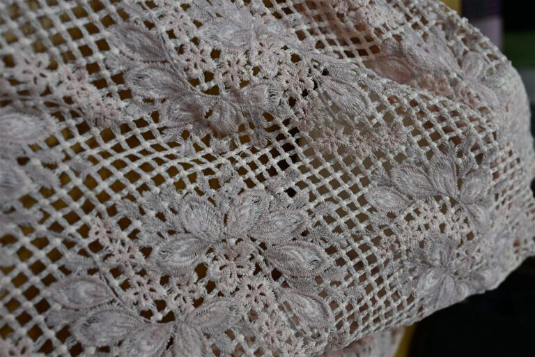 Detailed close-up of premium Chanel-style bouclé fabric featuring intricate floral embroidery and a delicate open weave pattern, perfectly illustrating Fursone’s expertise in custom bespoke fabric development. This image embodies the artisan aesthetic and luxury textile quality sourced from China’s leading tweed and knit fabric manufacturer.
