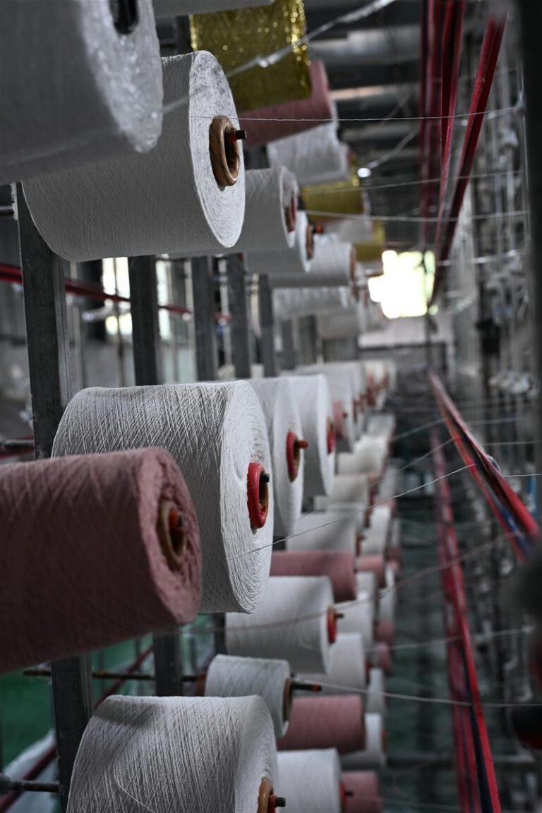 Rows of yarn spools in a fabric manufacturing facility illustrate Fursone's heritage cable knits production. This image represents our expertise in knit fabric manufacturing and highlights our commitment to affordable luxury with 100M meters of ready stock and custom bespoke solutions.
