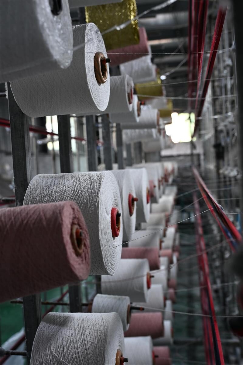 Rows of yarn spools in a fabric manufacturing facility illustrate Fursone's heritage cable knits production. This image represents our expertise in knit fabric manufacturing and highlights our commitment to affordable luxury with 100M meters of ready stock and custom bespoke solutions.