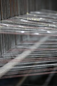 Detailed view of yarn threads stretched on a weaving loom representing the precision and craftsmanship in heritage cable knits manufacturing. This image highlights Fursone's expertise in producing premium knit fabrics and supports their positioning as a top supplier of heritage cable knits from Wenzhou since 1995.