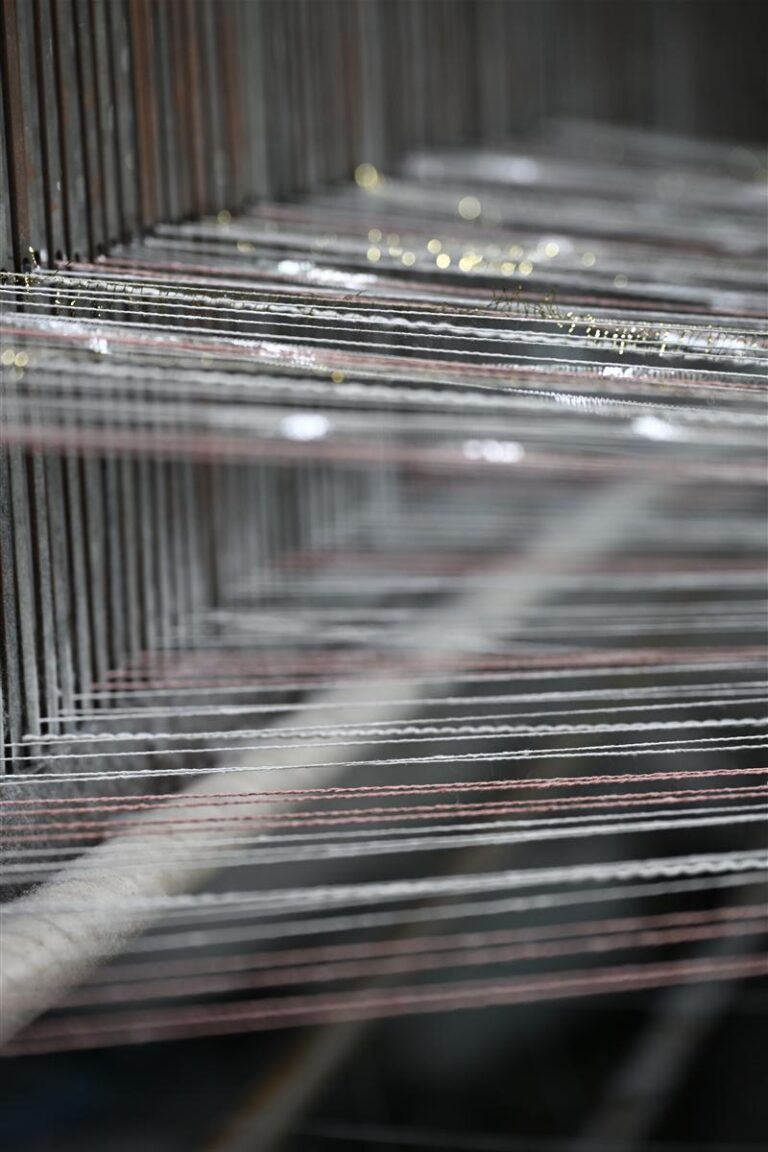 Detailed view of yarn threads stretched on a weaving loom representing the precision and craftsmanship in heritage cable knits manufacturing. This image highlights Fursone's expertise in producing premium knit fabrics and supports their positioning as a top supplier of heritage cable knits from Wenzhou since 1995.