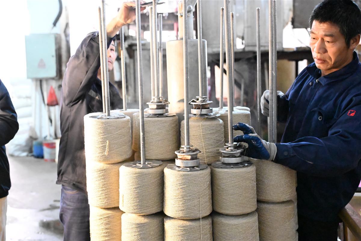 Tweed fabric manufacturing process showing knitting machine needles and yarn feeds in a factory setting