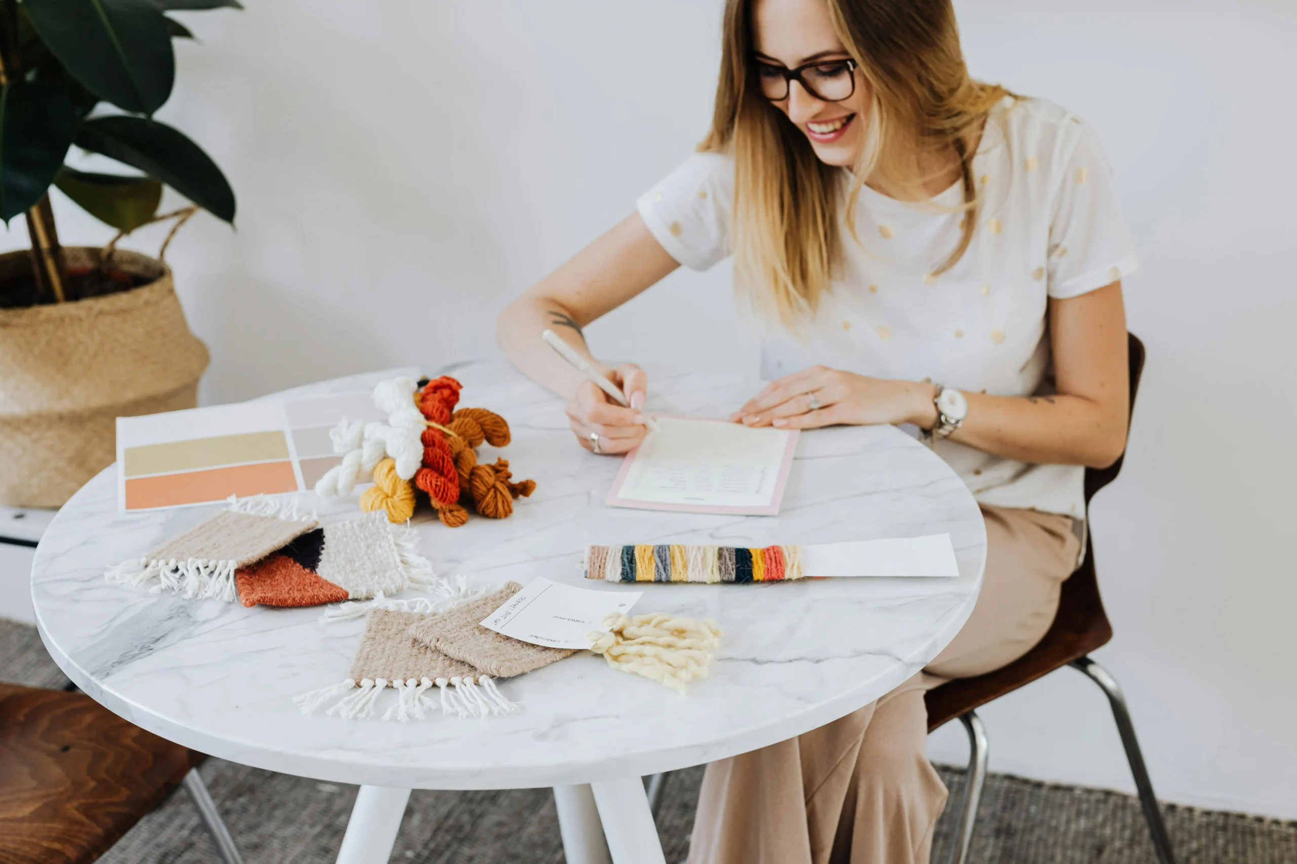 On a marble table, a designer reviews knit fabric swatches, yarns, and color cards. This image embodies Fursone's Rapid Sampling: 7-Day Turnaround for Fabric Development and our expertise in premium tweed, bouclé, and heritage knits.