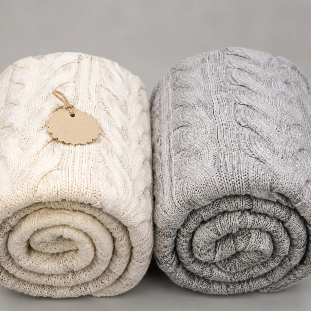Hyper-realistic product photography, a side-by-side comparison of two rolls of premium cable knit fabric, one labeled with a subtle quality badge, studio lighting with soft shadows, high-end textile showroom aesthetic, no text, no brand logo